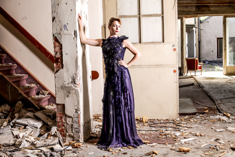 Frau im bodenlangen Kleid im verfallenen Treppenhaus